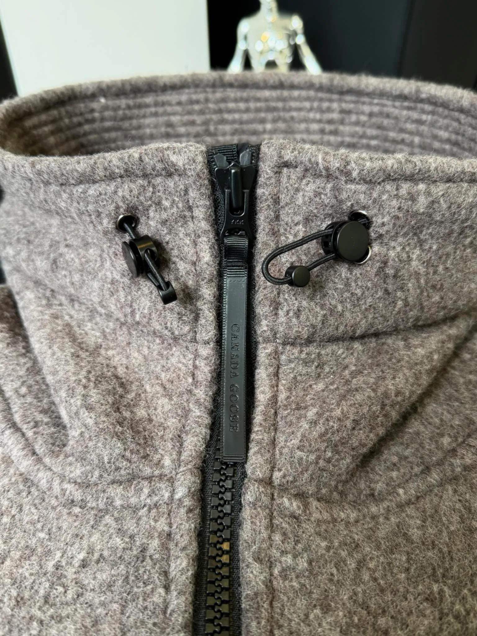 P660 Canada Goose Fleece Wool Hooded Jacket Fabric selection: Wool fleece fabric blended with wool as the main body and a very small amount of spandex and polyester fiber. Wool is a core natural ingredient that provides unparalleled temperature regulation, antibacterial and anti-odor properties and a skin-friendly feel. The feeding of a small amount of spandex gives the fabric a certain degree of four-way elasticity, making it non-restrictive during daily activities. As the basis of fleece's structure, polyester fiber enhances the fabric's durability, wrinkle resistance and quick-drying properties. It contributes to the loft of the fleece and provides functions such as trapping air.  Detail 1: The sleeves and hem are closed with 2×2 ribbing. Its strong elasticity can closely fit wrists and waists of different thicknesses, forming an effective 'seal' to prevent cold wind from blowing back. It can still maintain its original shape after repeated stretching and use, and is not easy to loose and deform. And the ribbed cuffs can convey a sense of design and enhance the visual beauty.  Detail 2: The combination of hood design and elastic buckle improves warmth and windproof performance when wearing. Accessories: Customized elastic drawstring, elastic buckle, custom zipper pendant, custom armband Size: S M L Color: black gray coffee rice pink